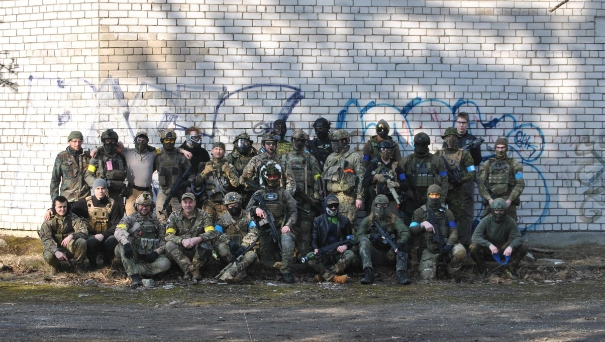 Airsoft player advancing with tactical replica in forest terrain